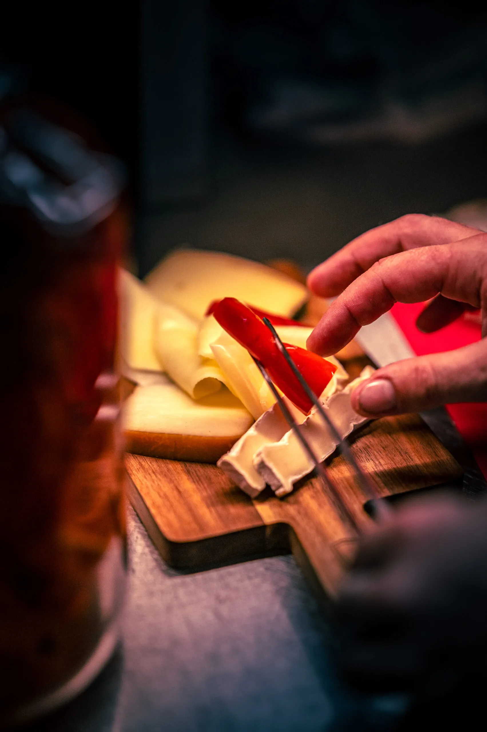 Hände schneiden Käse auf einem Holzbrett